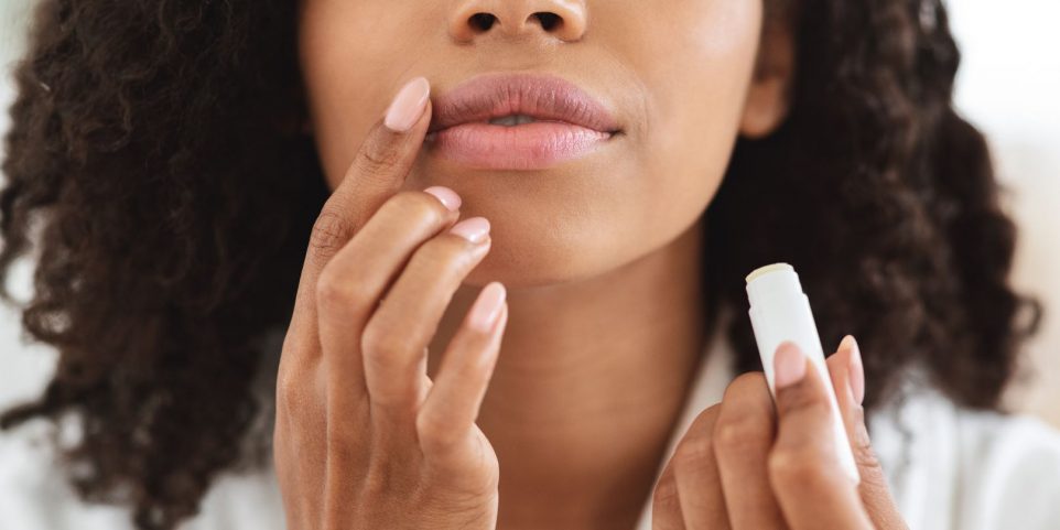 Lip Care. Unrecognizable black woman applying moisturising chapstick on lips, closeup