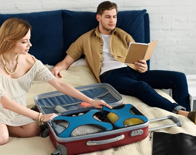 A man reads while a woman packs a neat suitcase using the Shacke packing cube for travel set